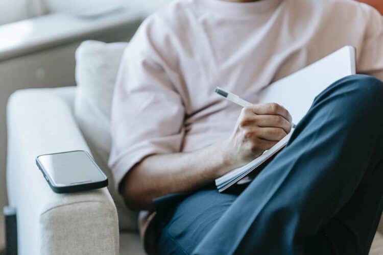 Photo by Michael Burrows: https://www.pexels.com/photo/crop-faceless-man-writing-in-notebook-and-sitting-in-armchair-7129034/