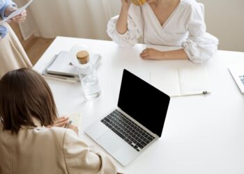 Photo by Artem Podrez: https://www.pexels.com/photo/woman-in-white-long-sleeve-shirt-sitting-beside-table-with-black-and-silver-laptop-8512440/