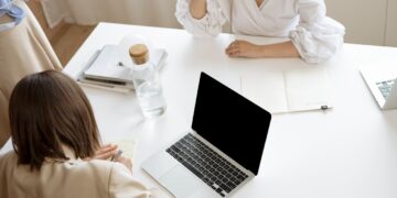 Photo by Artem Podrez: https://www.pexels.com/photo/woman-in-white-long-sleeve-shirt-sitting-beside-table-with-black-and-silver-laptop-8512440/