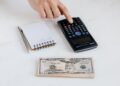 Photo by Photo By: Kaboompics.com: https://www.pexels.com/photo/crop-unrecognizable-accountant-using-calculator-near-pile-of-american-dollars-4386322/